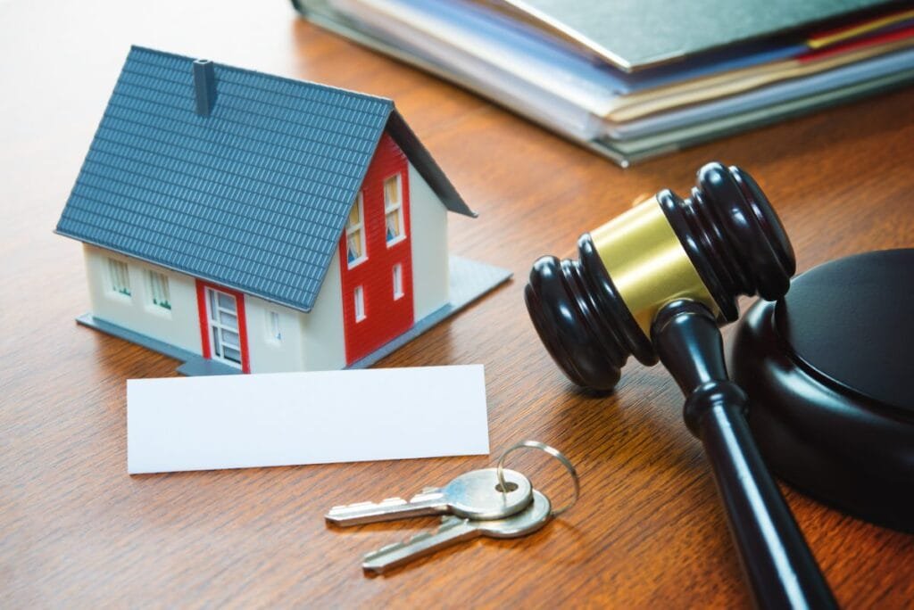 Model house, house keys and a judge's gavel on a desk